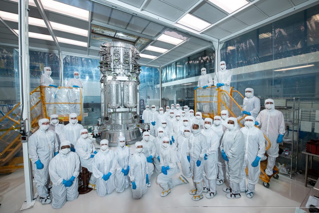 A team of NASA engineers dressed in cleanroom suits standing around a component of the Europa clipper.