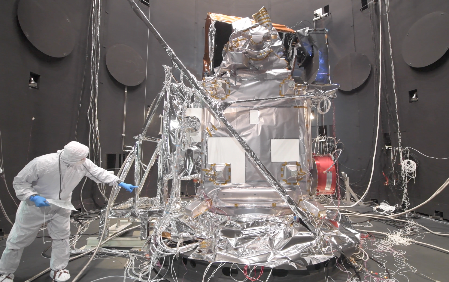 Person in cleanroom suit next to PACE in the thermal vacuum chamber for testing.
