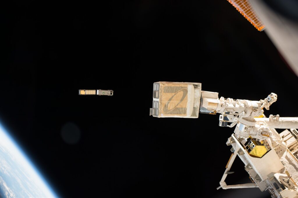 The IceCube instrument on the left, developed by the Microwave Instrument and Technology Branch, is being deployed from the International Space Station.
