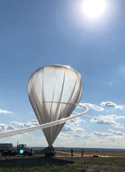 Scientific balloon, which is a clear, upside down teardrop shade, with a long tube leading to it being used to inflate it.