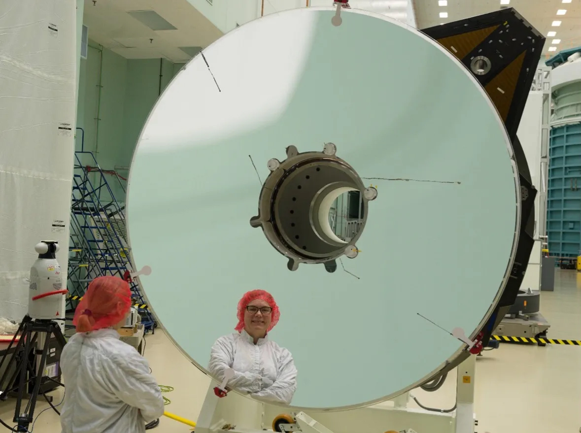 Bente Eegholm stands by the NASA’s Nancy Grace Roman Space Telescope’s primary mirror at L3Harris in Rochester, New York, in 2022, before telescope integration. (The black lines are resistor wires. They will be obscured by the secondary mirror struts).