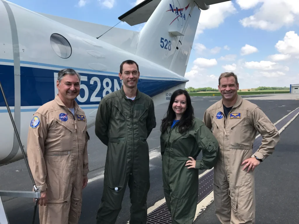 Matthew Kowalewski stands second from left with three other people. He and the woman in the middle are wearing flight suits.