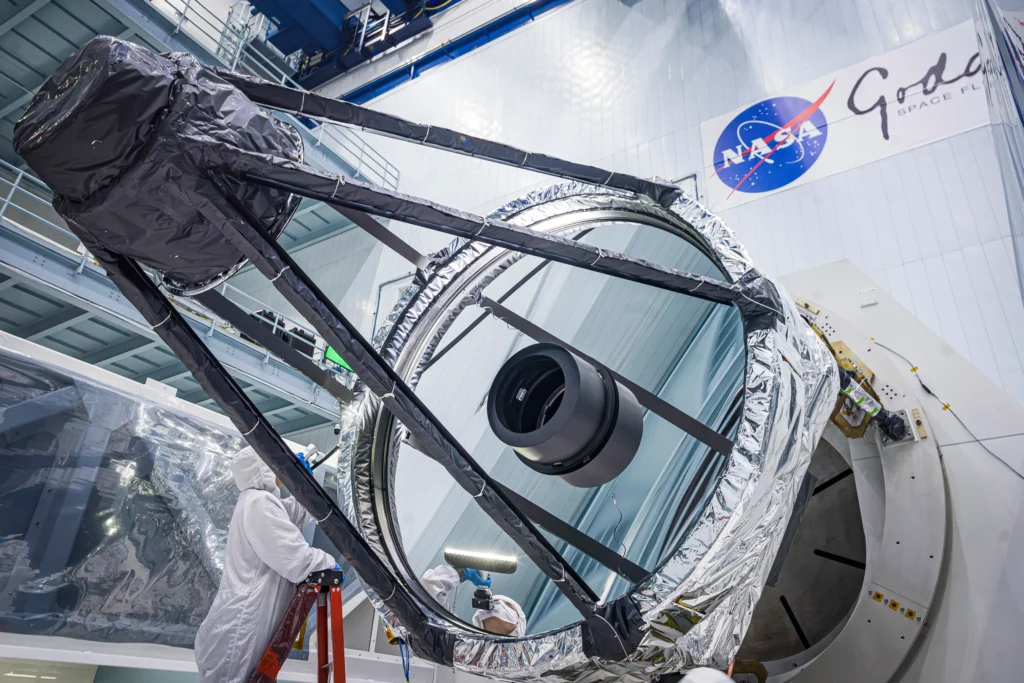 In this photo, optical engineer Bente Eegholm inspects the surface of the primary mirror for NASA’s Nancy Grace Roman Space Telescope. This 7.9-foot (2.4-meter) mirror is a major component of the Optical Telescope Assembly, which also contains nine additional mirrors and supporting structures and electronics. NASA/Chris Gunn