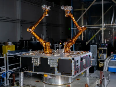 Two robotic arms wrapped in gold material sitting on top of a black and silver box.